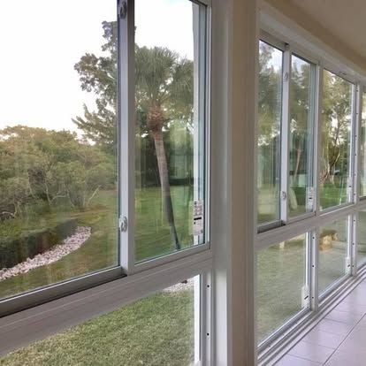 Sunlit hallway with large windows overlooking a grassy garden and trees outside.