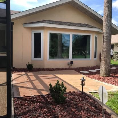 Front view of a beige house with white trim, large window, and desert landscaping by a walkway