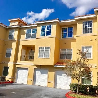 Yellow townhouse row with white garage doors under a blue sky
