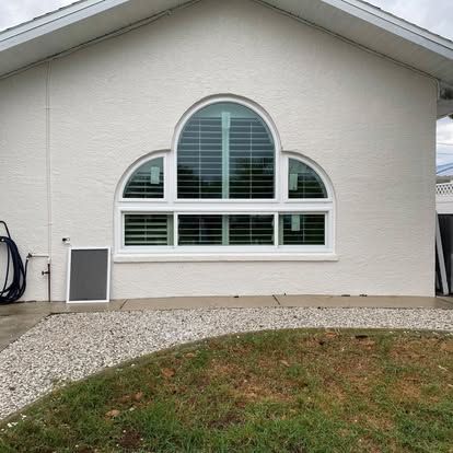 White house exterior with arched window and gravel landscaping