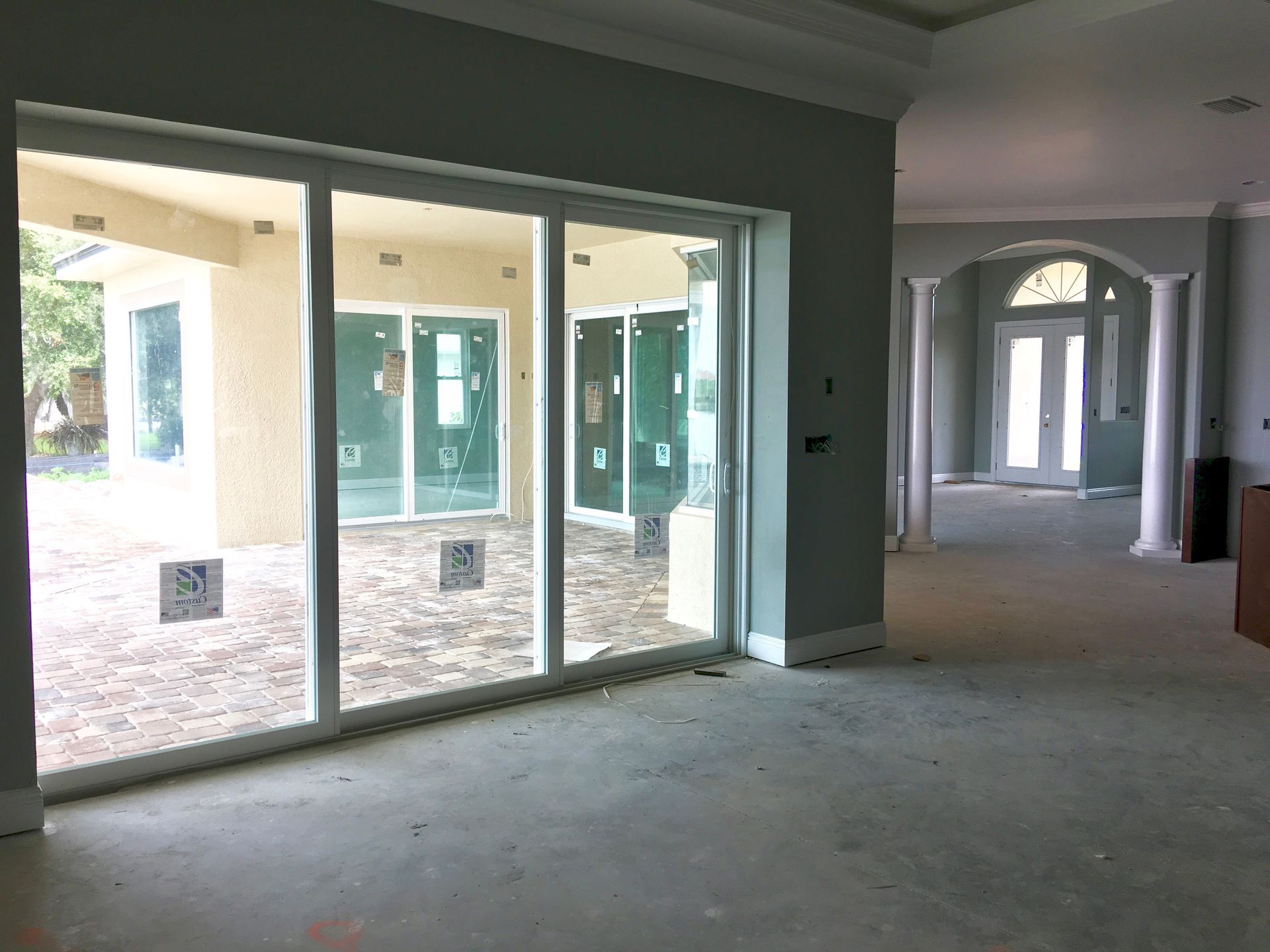 Empty unfurnished interior with sliding glass doors and arched hallway openings, lit by daylight