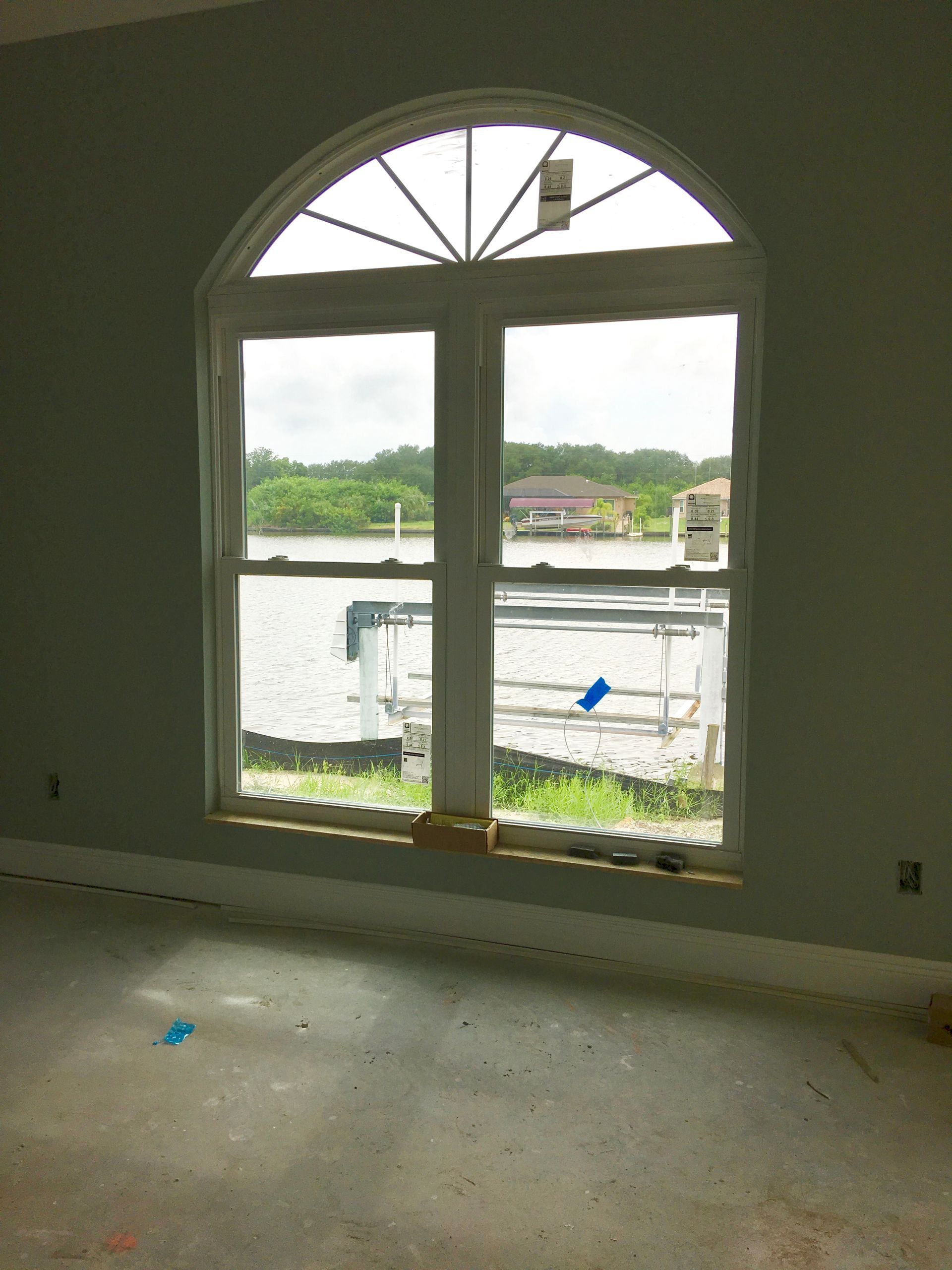 Empty room with arched window overlooking a waterfront construction site