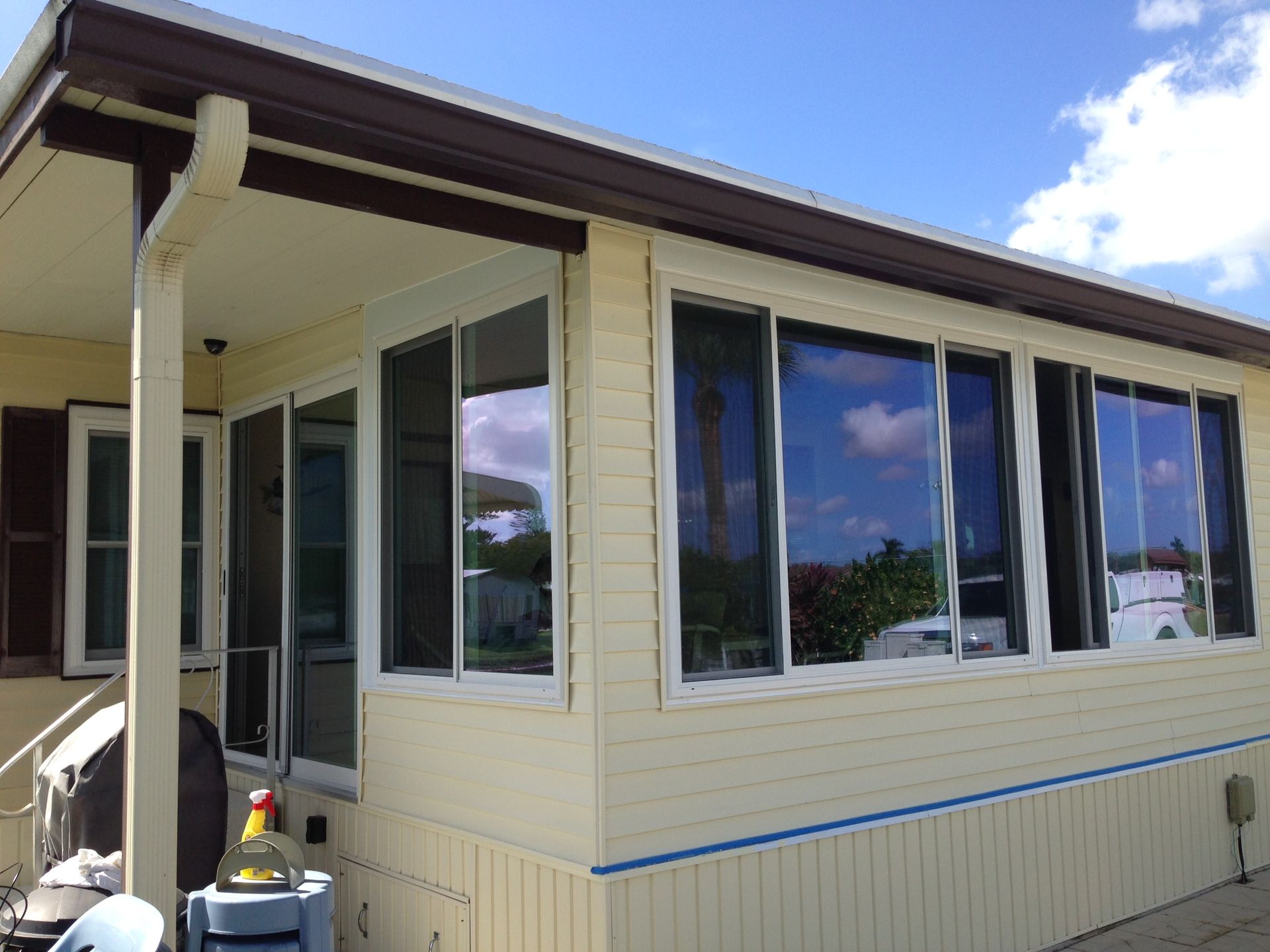 Exterior corner of a beige house with large windows and a small covered porch