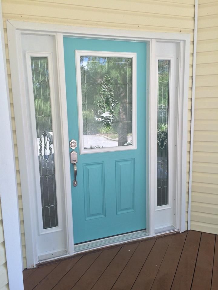 Turquoise front door with glass sidelights on a covered porch and wood deck.