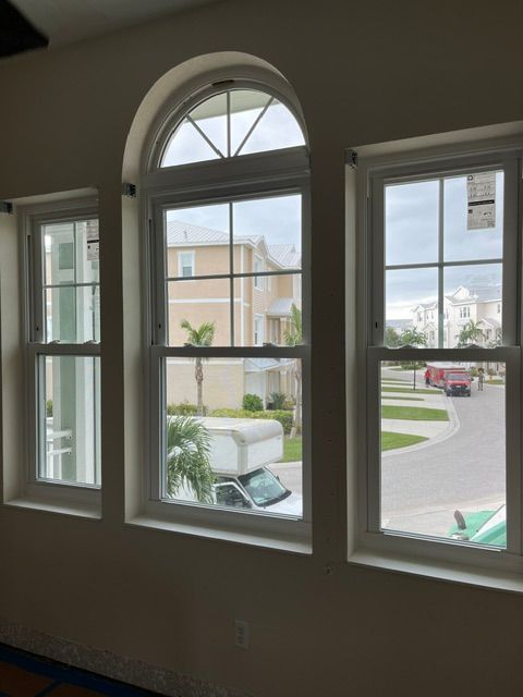Interior view of arched window overlooking a suburban street and parked cars