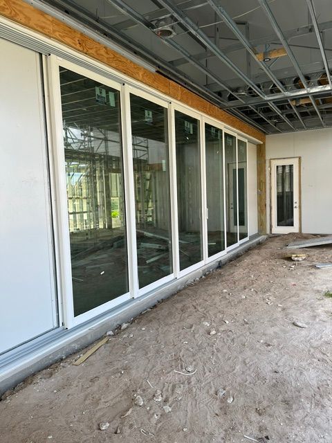 Unfinished interior with large sliding glass doors and exposed ceiling on a dirt floor