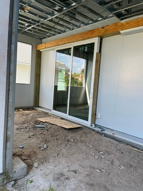 Interior under construction with sliding glass doors, exposed beams, and unfinished dirt floor