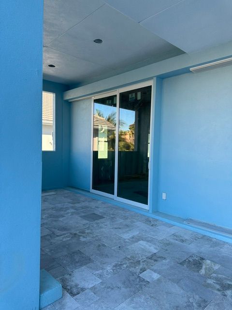 Covered blue patio with gray tile floor and sliding glass doors
