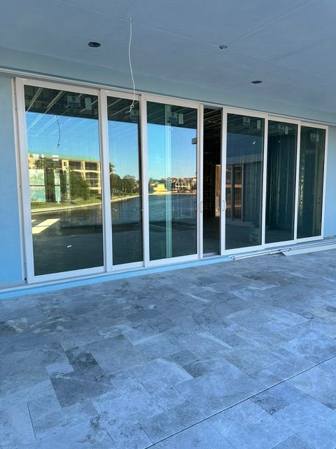 Glass storefront with sliding doors and blue-tinted reflections under a covered walkway