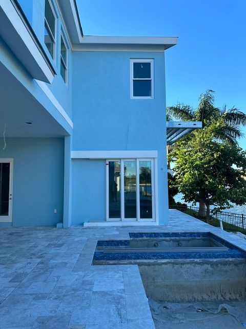 Modern blue house patio with sliding glass doors, pool, and ocean view