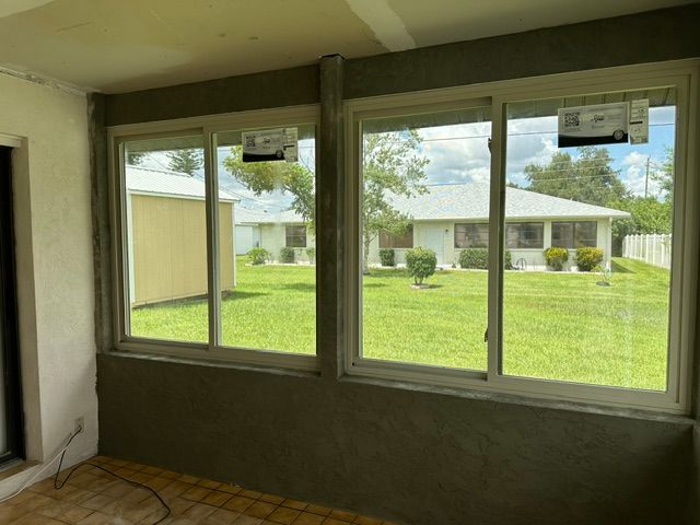 Living room with large windows overlooking a green yard and neighboring homes