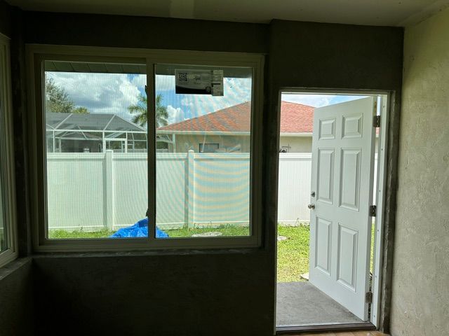Empty room with dark green walls, a window, and an open white door to a backyard.