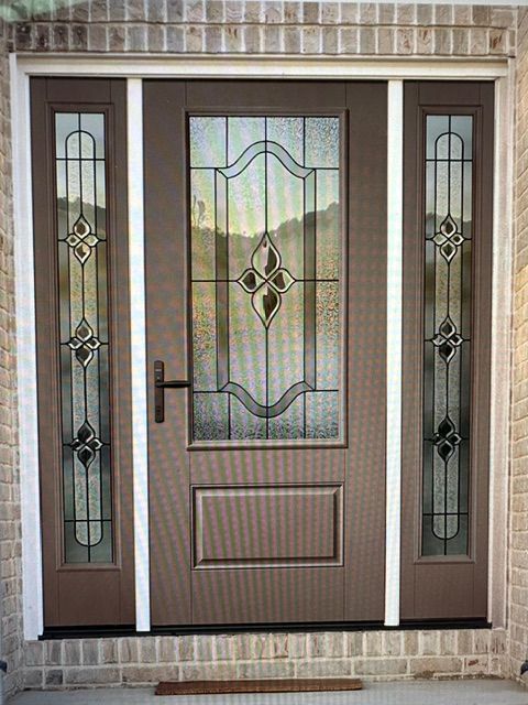 Front view of a brown double front door with decorative glass sidelights and a brick exterior frame