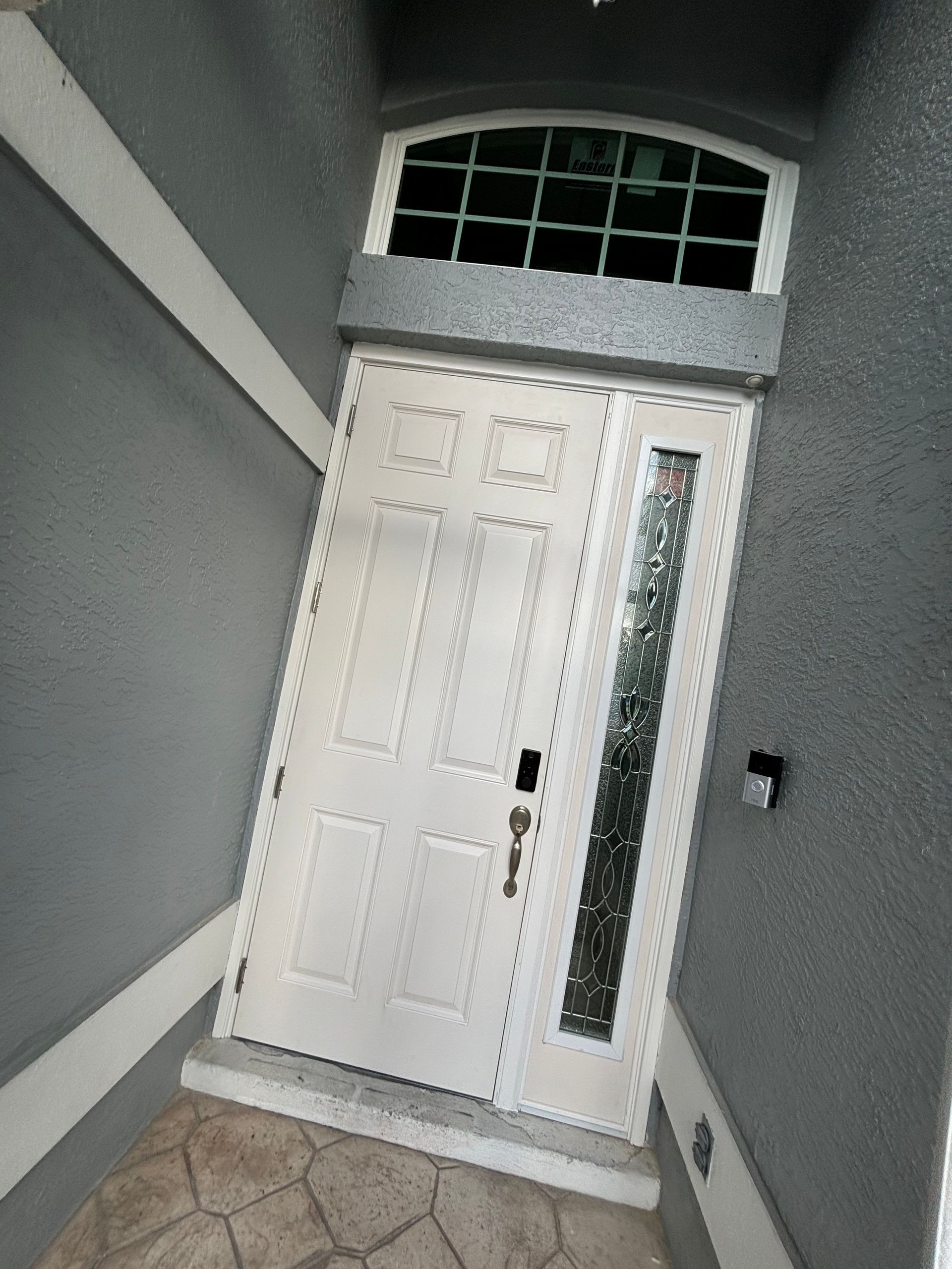 Front entrance with white door, sidelights, and gray walls under an arched transom window.