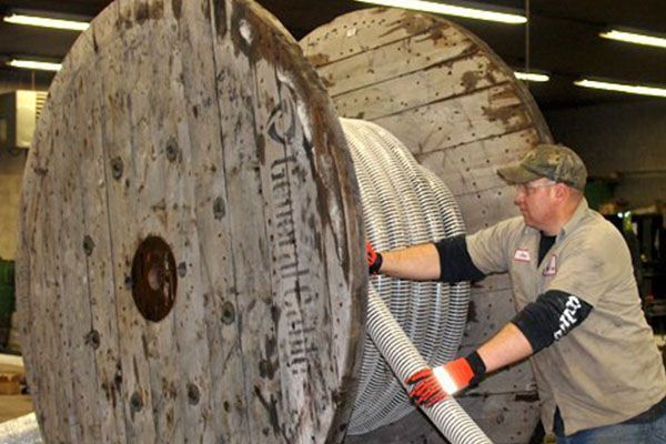 A man is working on a large wooden spool of wire