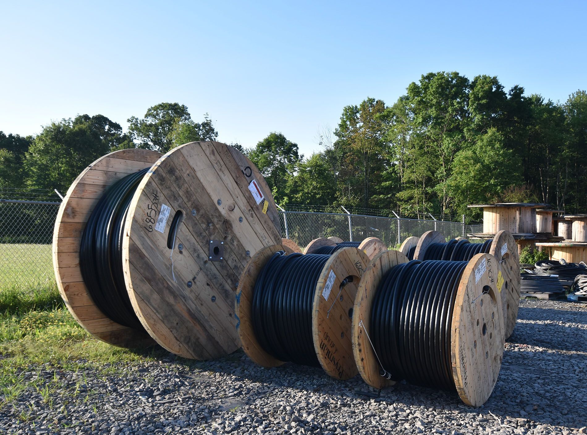 A bunch of wooden spools of wires are stacked on top of each other.