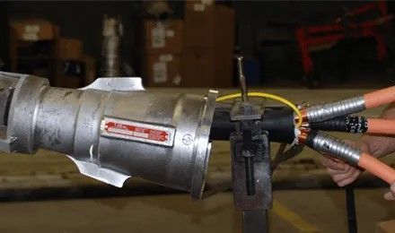 A person is cutting a cable with a machine in a factory.