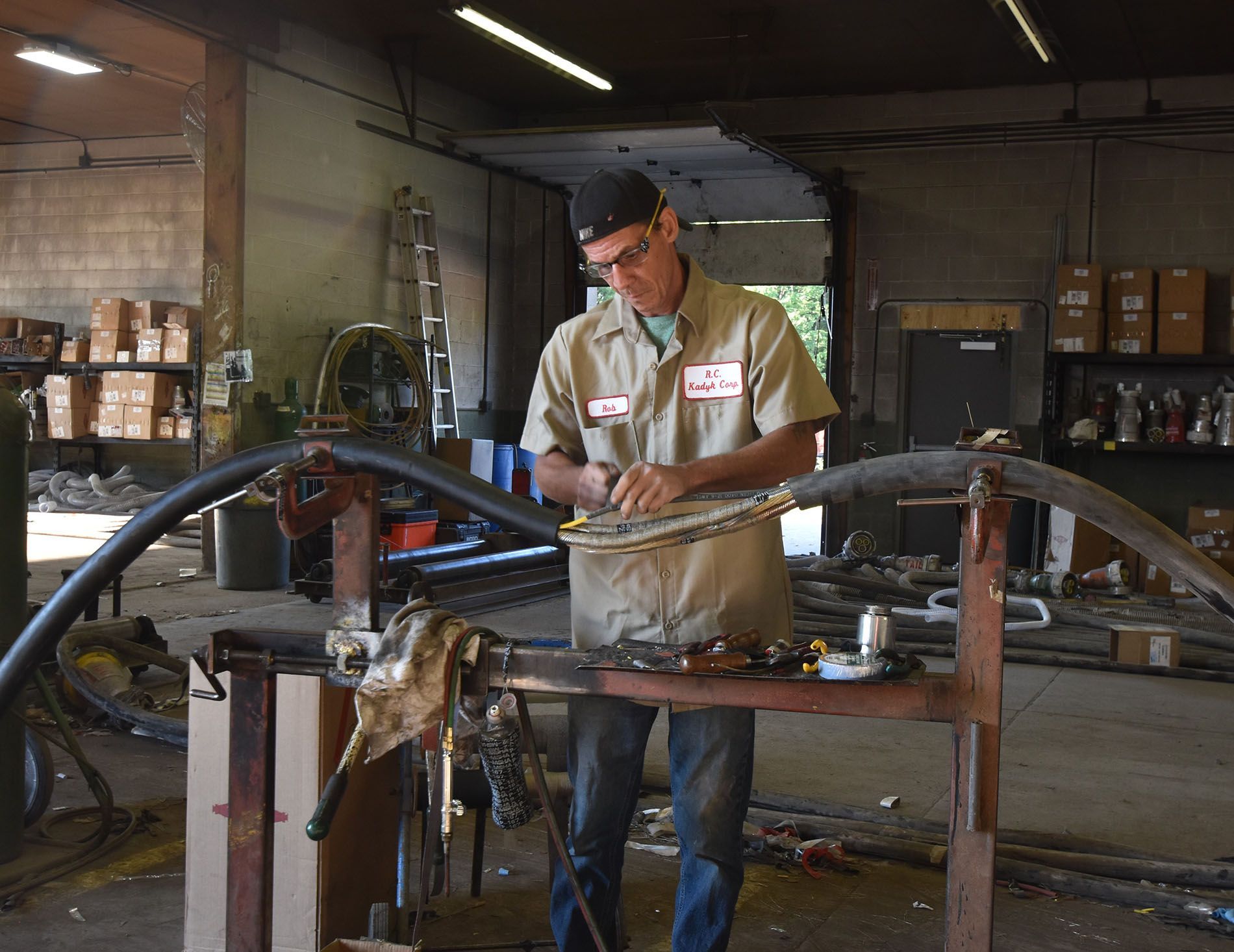 A man is working on a hose in a garage.