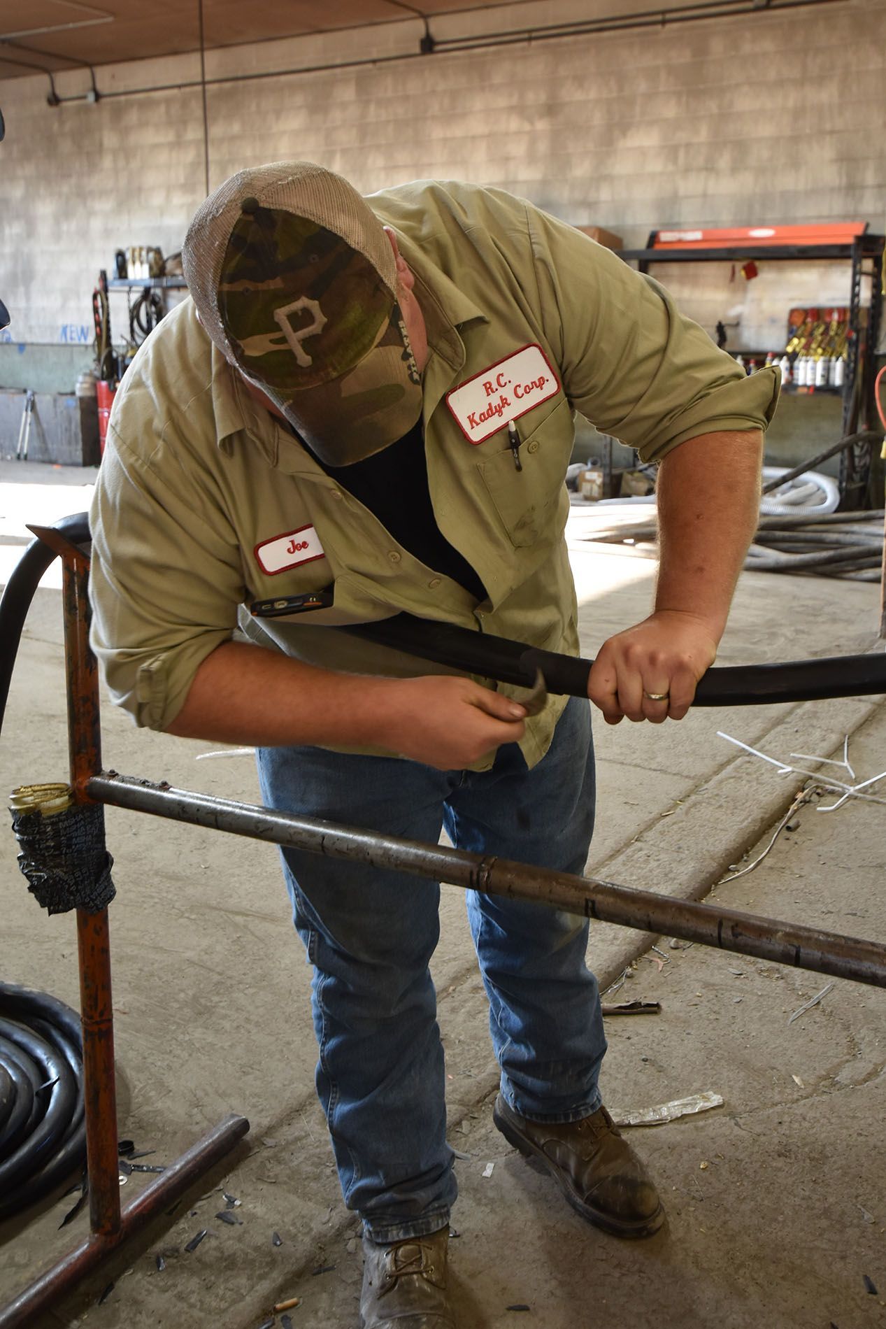 A man wearing a hat with the letter p on it is working on a pipe.