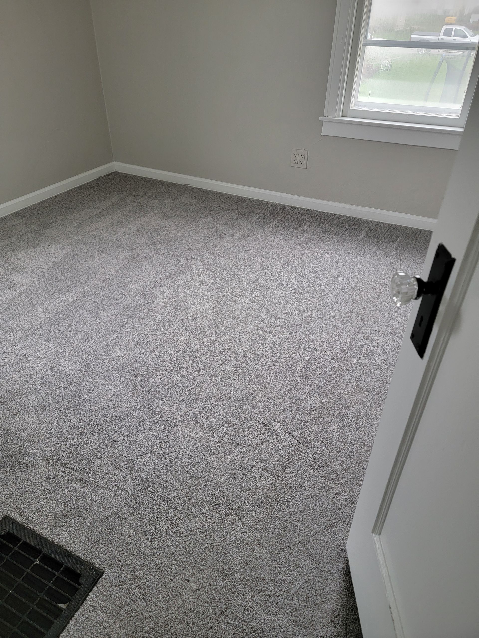 A bedroom with a carpeted floor and a window.