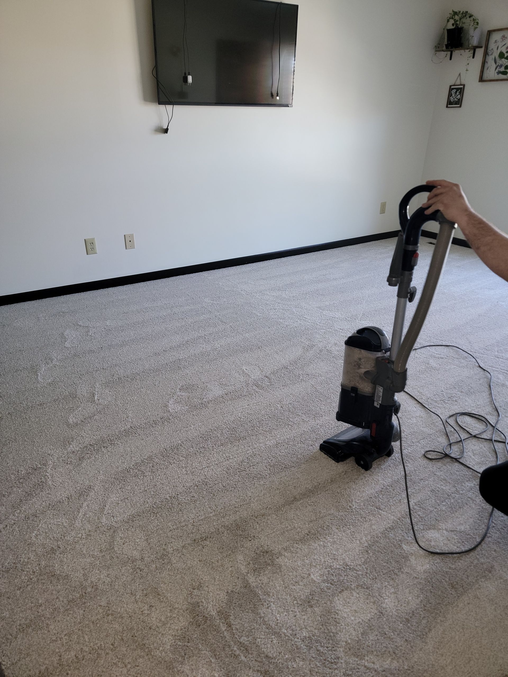 A person is using a vacuum cleaner to clean a carpet in a living room.