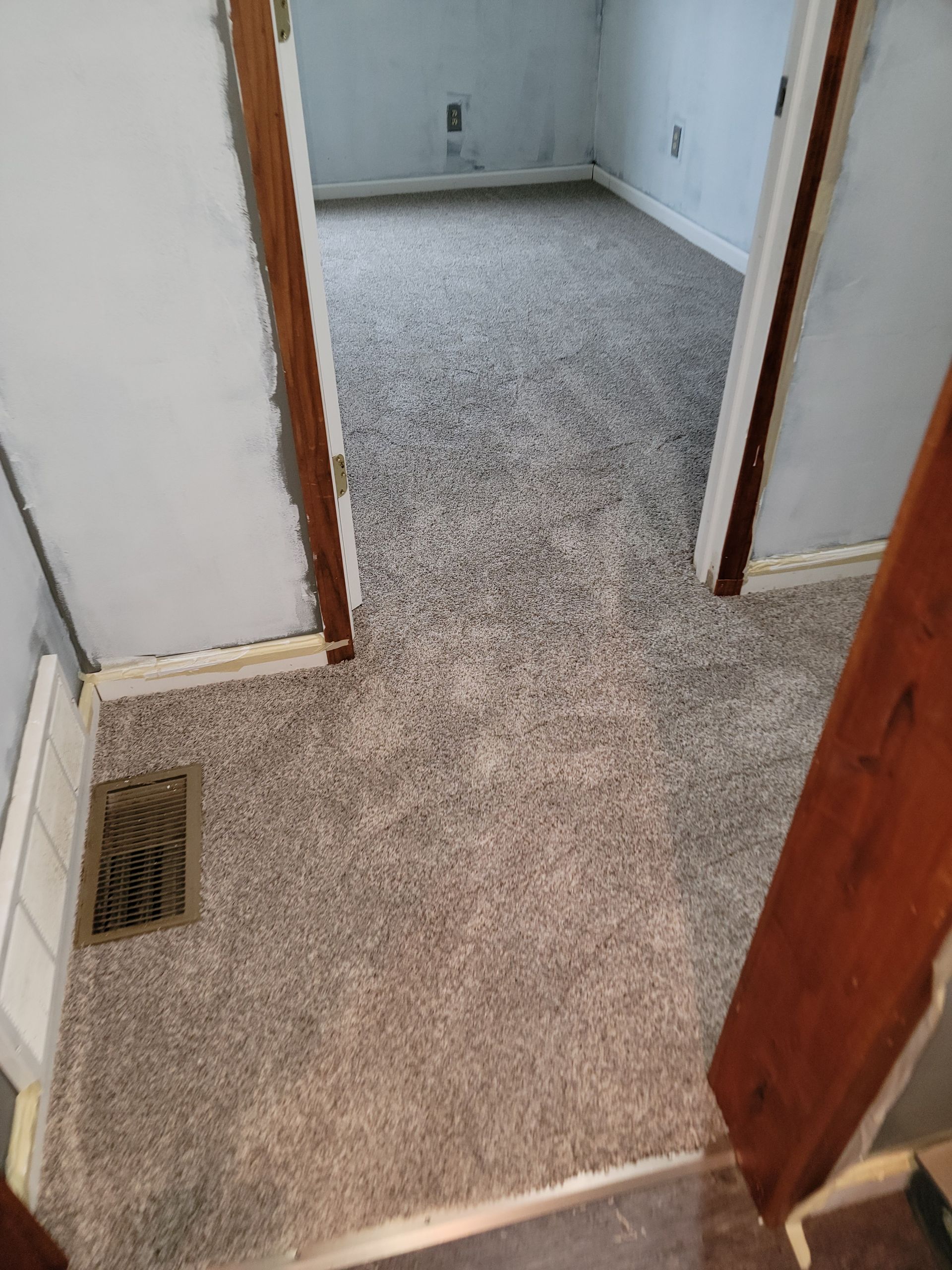 A room with a carpeted floor and two doors leading to it.