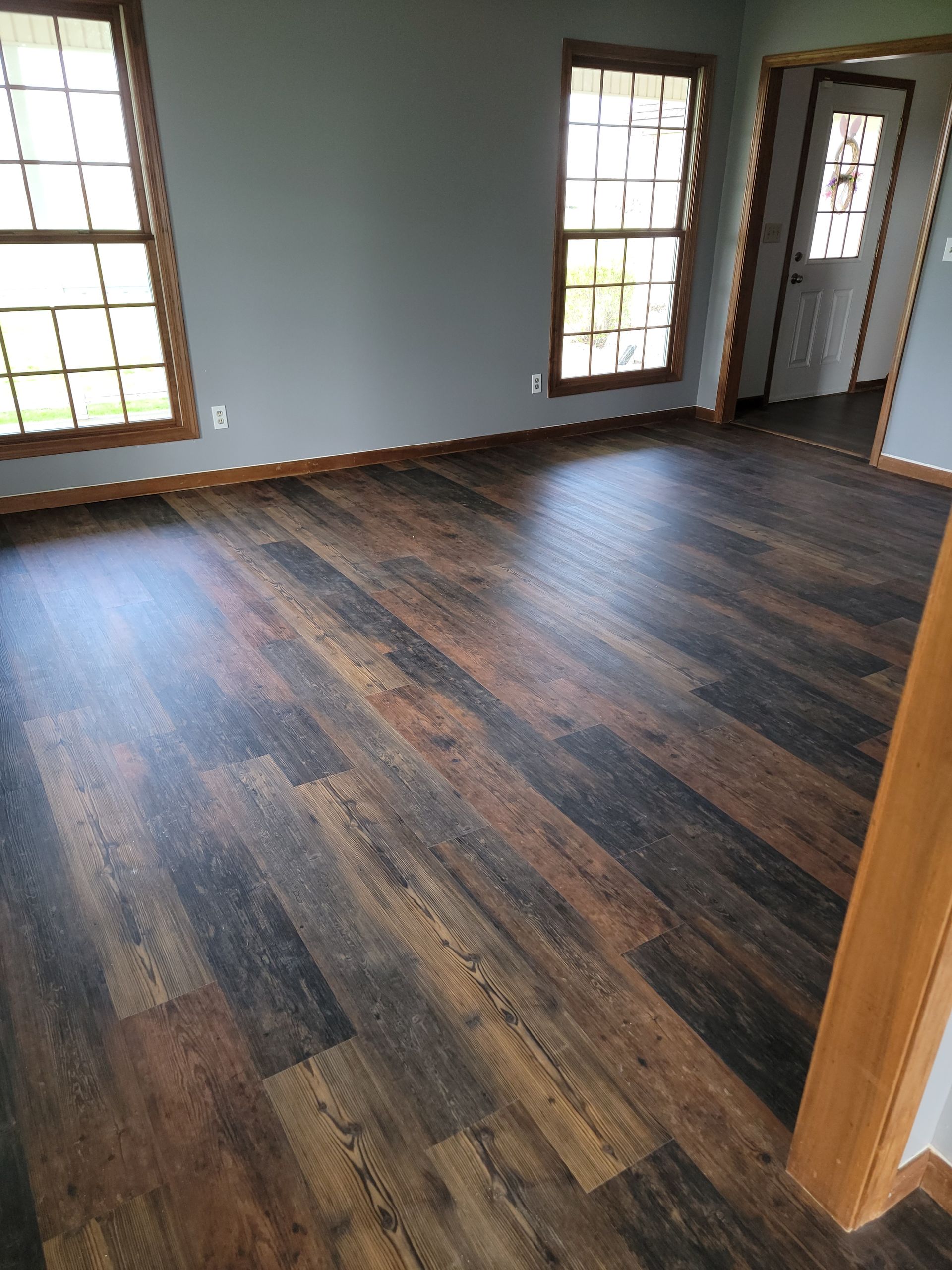 A living room with hardwood floors and two windows.