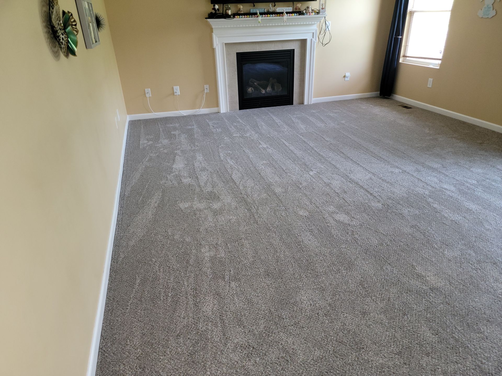A living room with a fireplace and a large carpeted floor.