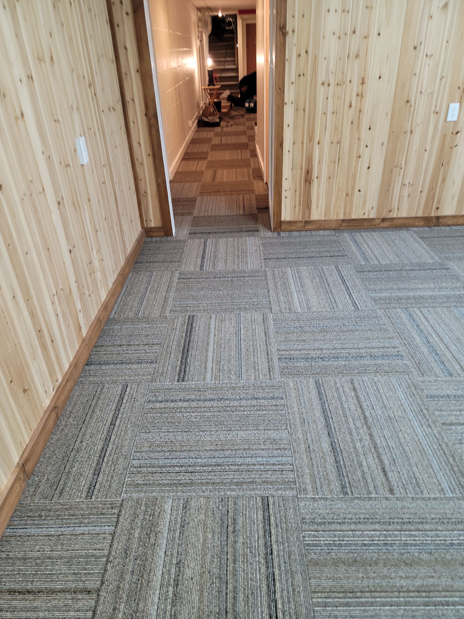 A room with a carpeted floor and wooden walls.