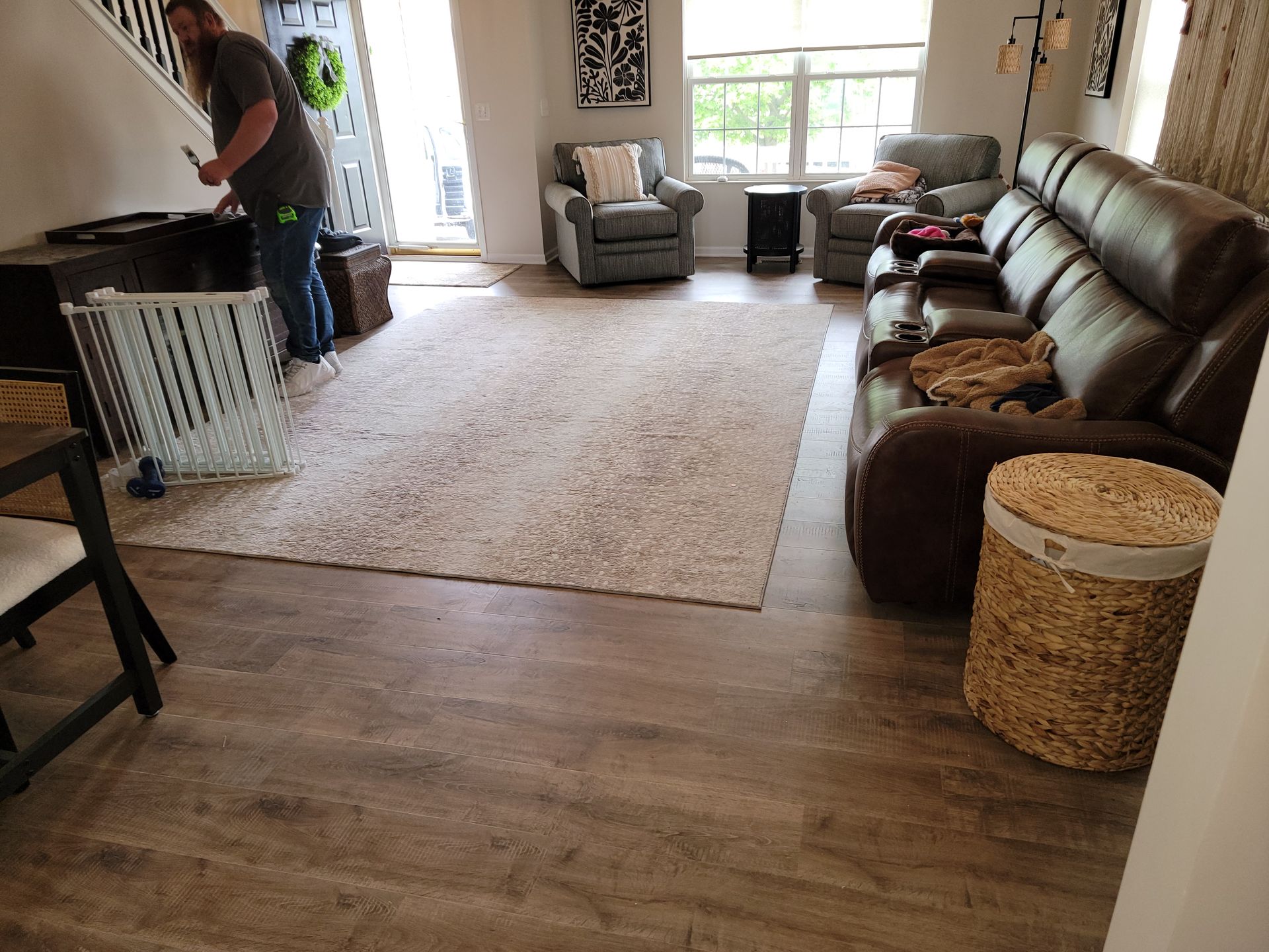 A man is standing in a living room next to a couch and chairs.
