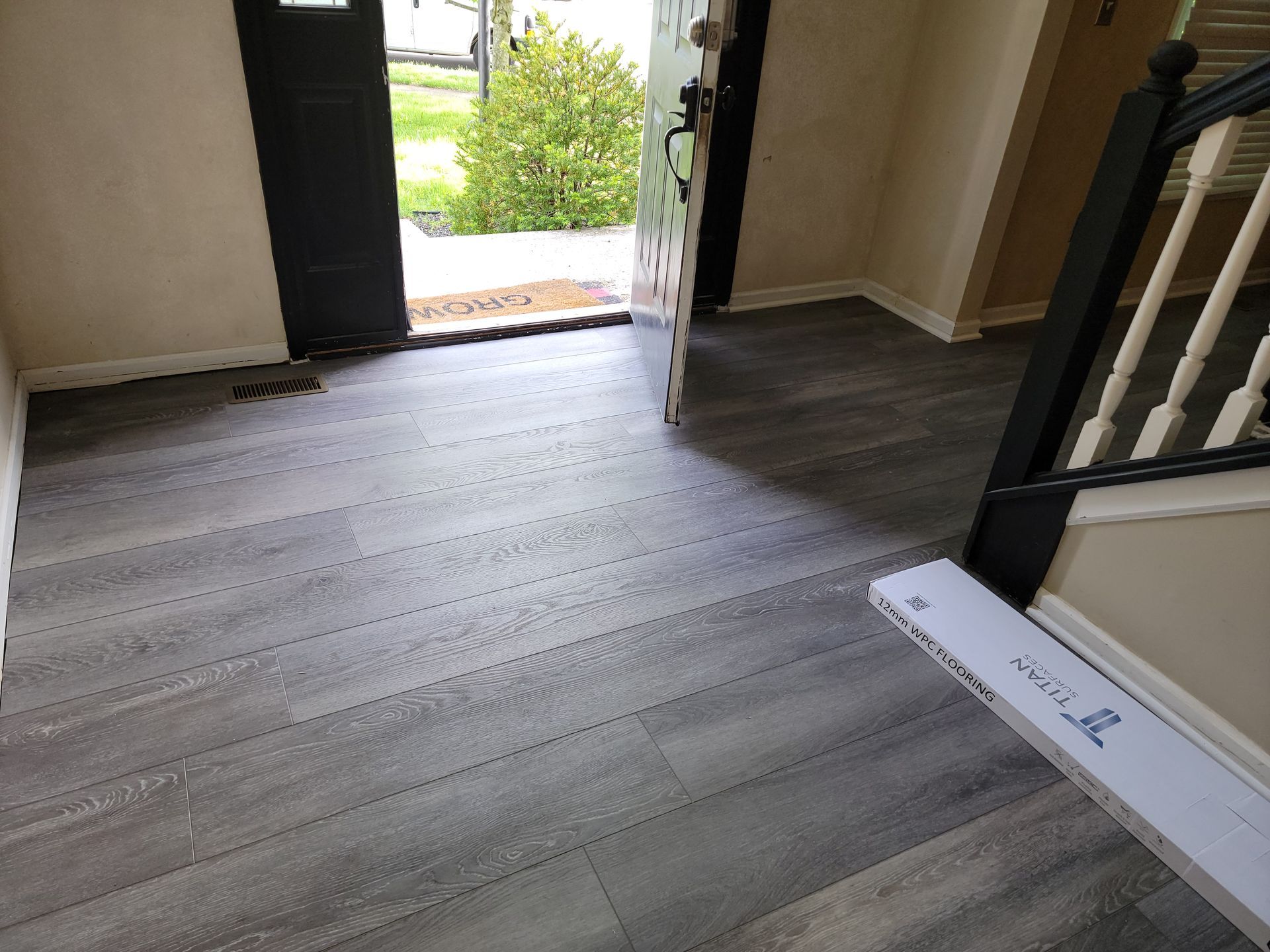 A hallway with a wooden floor and stairs in a house.