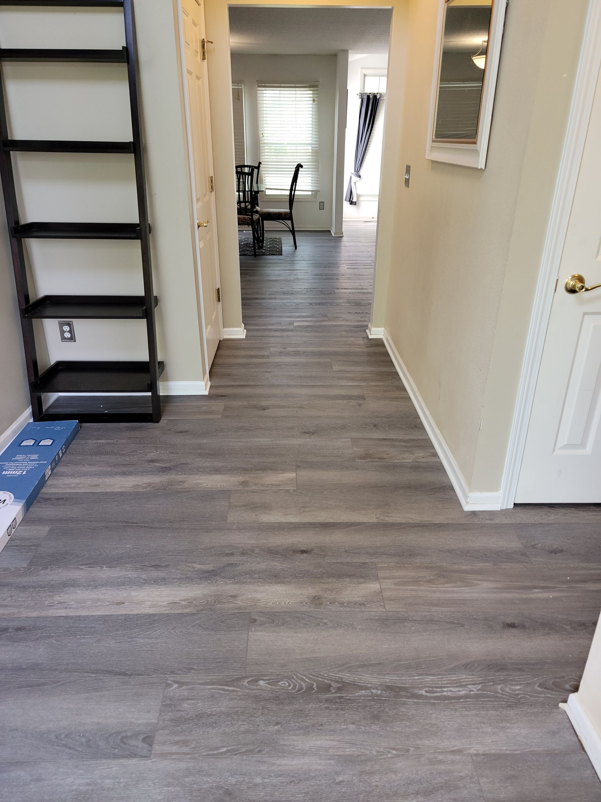 A hallway with a wooden floor and a ladder.