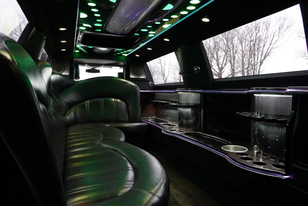 The inside of a limousine with green seats and a ceiling light.