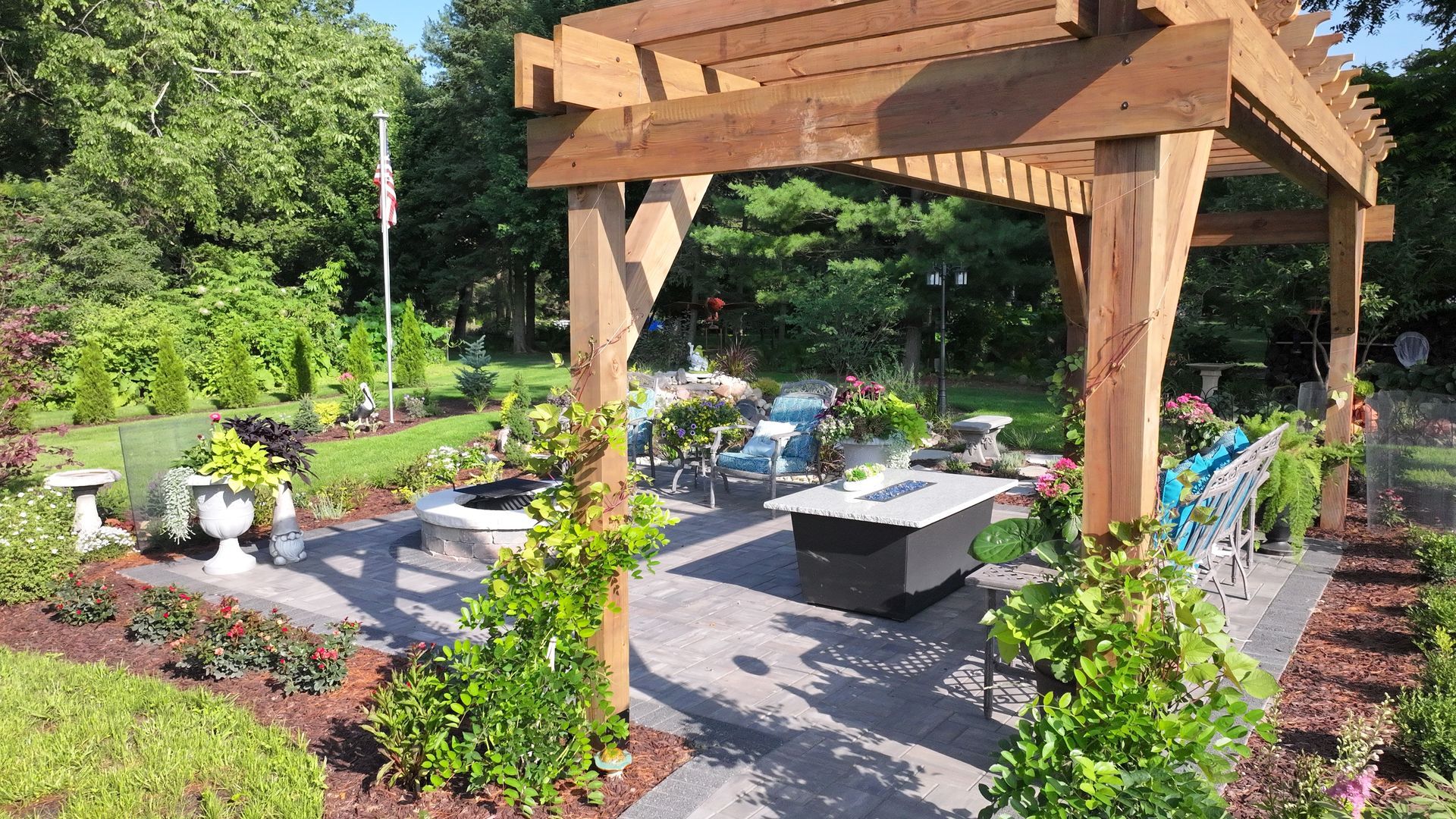 Outdoor patio with pergola, seating, fire pit, and surrounding greenery.
