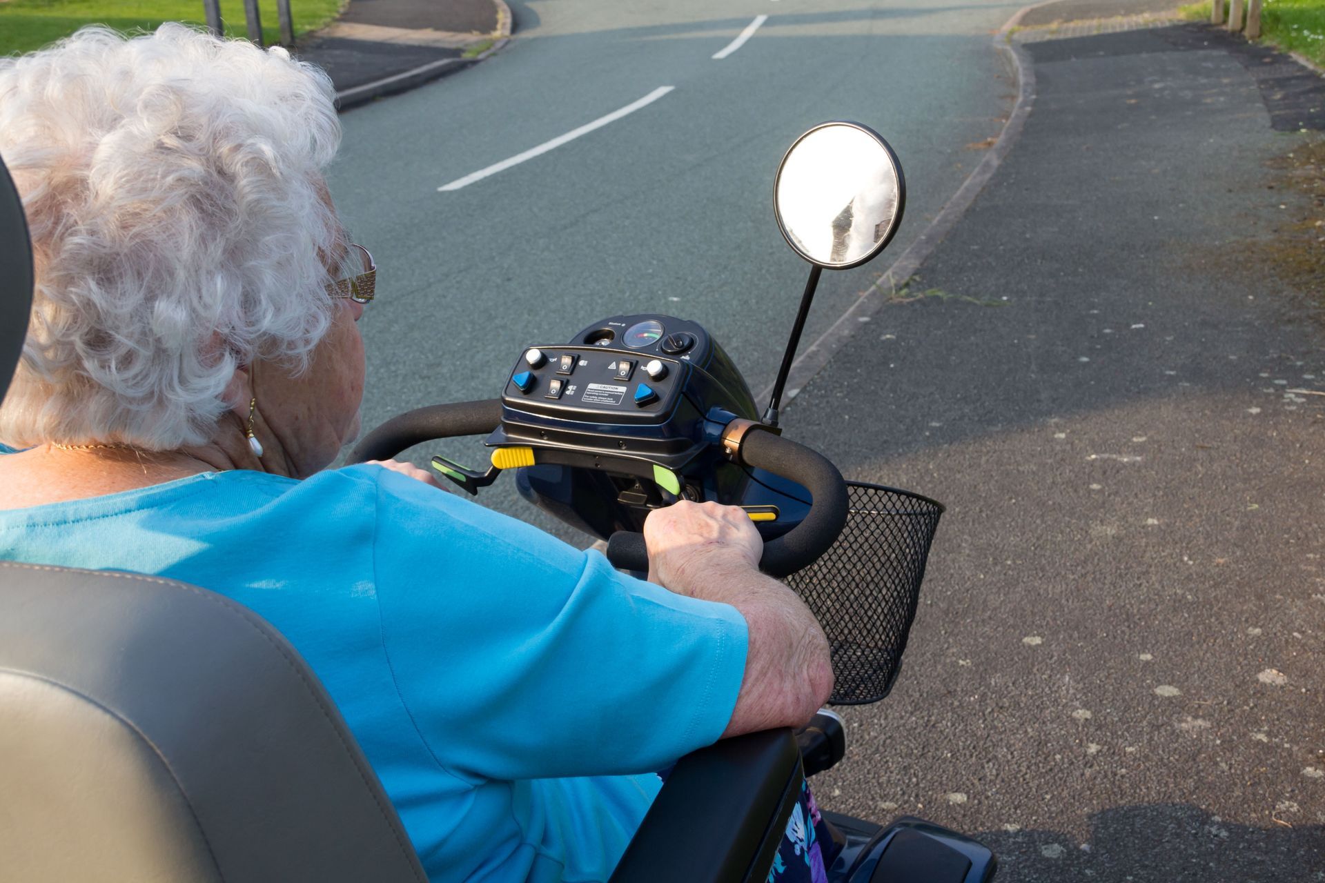 Person on mobility scooter, driving on a paved path.