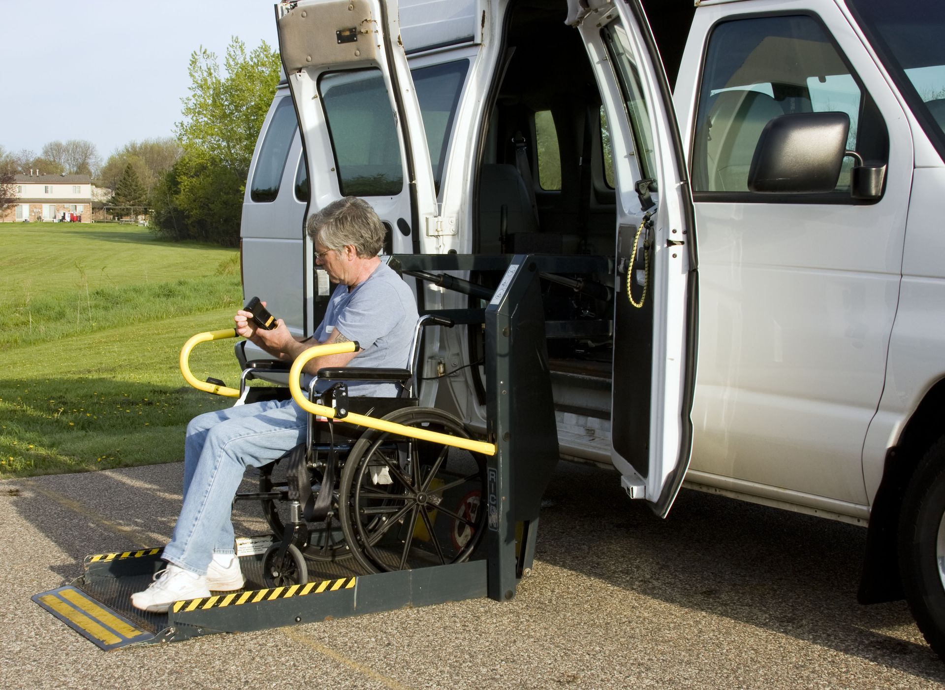 Man in wheelchair using lift to enter white van.
