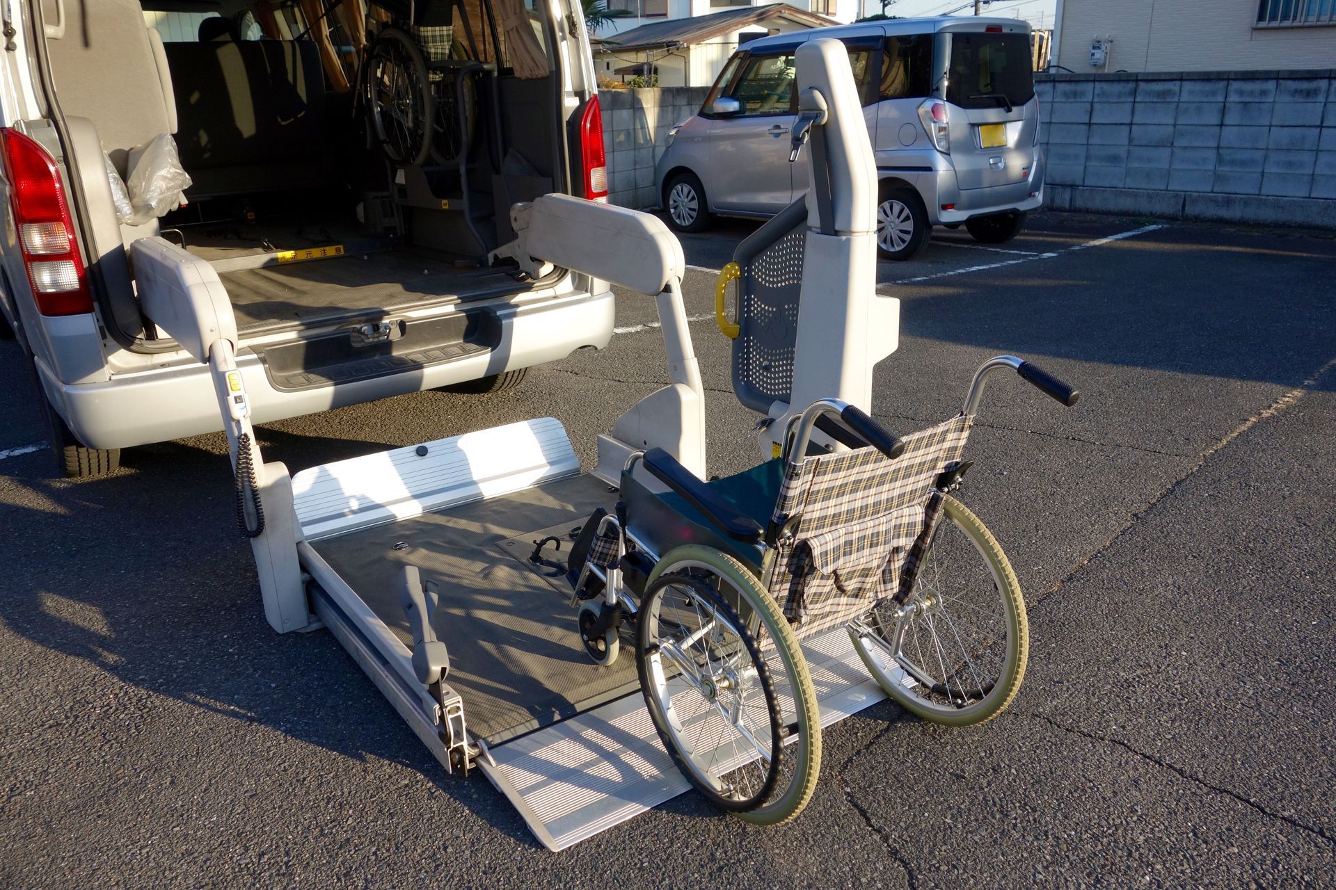 Wheelchair on lift extending from back of accessible van in parking lot.
