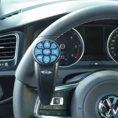 Steering wheel with assistive device attached; black with blue buttons. In car.