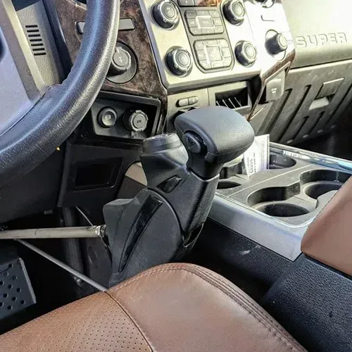 Interior view of a car with a brown leather seat, steering wheel, and gear shift lever.