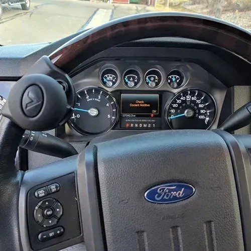 Ford truck dashboard with steering wheel and controls, showing speedometer and message.