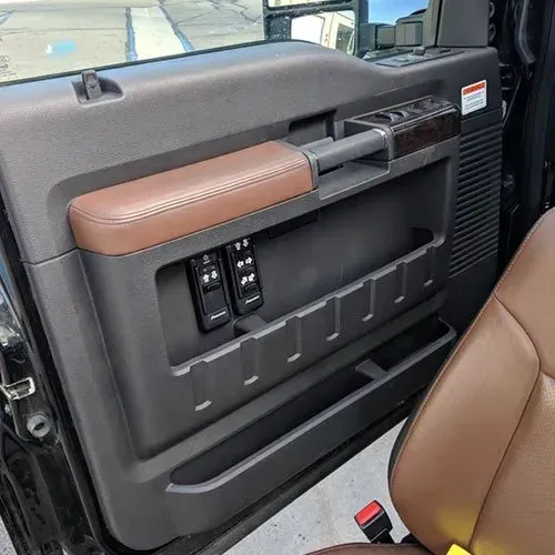 Interior door panel of a brown and black truck, showing window controls and storage compartments.