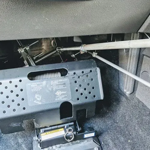 A vehicle's lowered accessible seat system; metal frame, levers, and mechanisms under the dashboard.