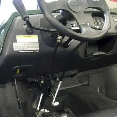 Interior of a vehicle with hand controls: steering wheel, levers, and pedals. Black and green color scheme.