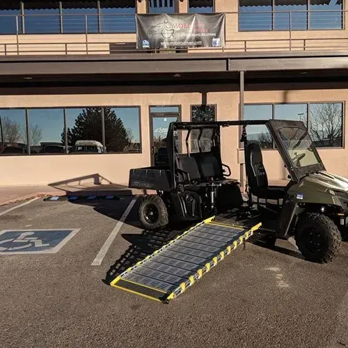 Black utility vehicle with a ramp in a handicapped parking spot in front of a building.