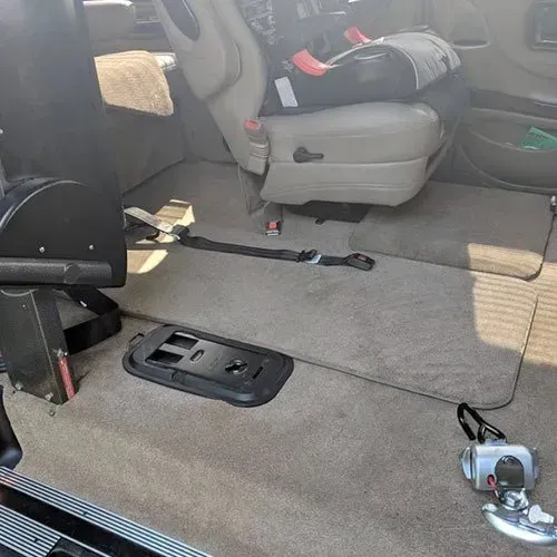 Interior of a van with accessible features: a wheelchair restraint system and passenger seating.