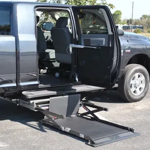 Wheelchair lift extending from the side door of a modified pickup truck.