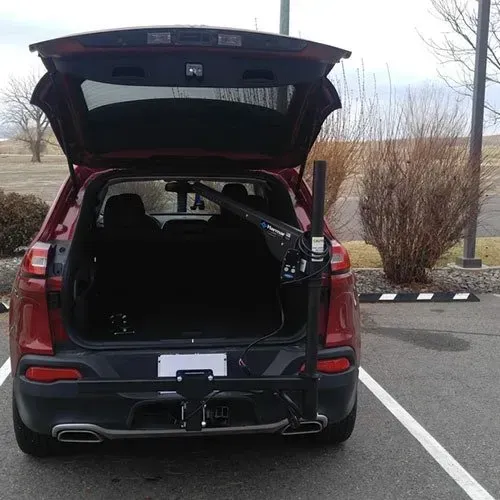 Red SUV with open trunk, a black lift installed on the rear, parked in a lot.