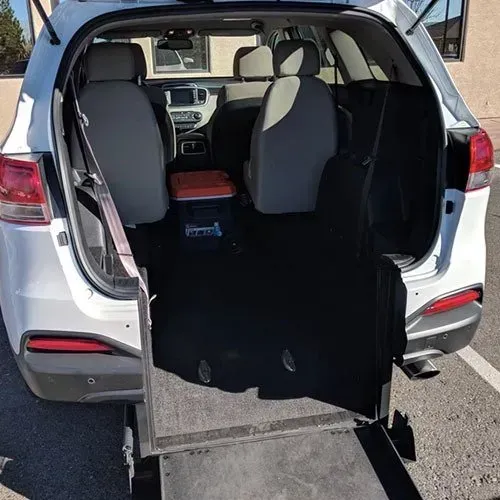White accessible van with ramp deployed, interior seats visible.