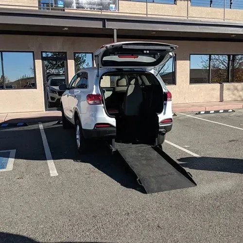 White SUV with ramp extended in a parking space in front of a building.
