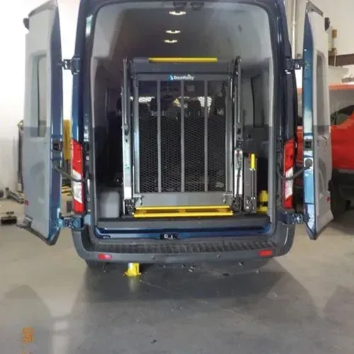 Blue van with open doors, equipped with a wheelchair lift. Interior lights are visible.
